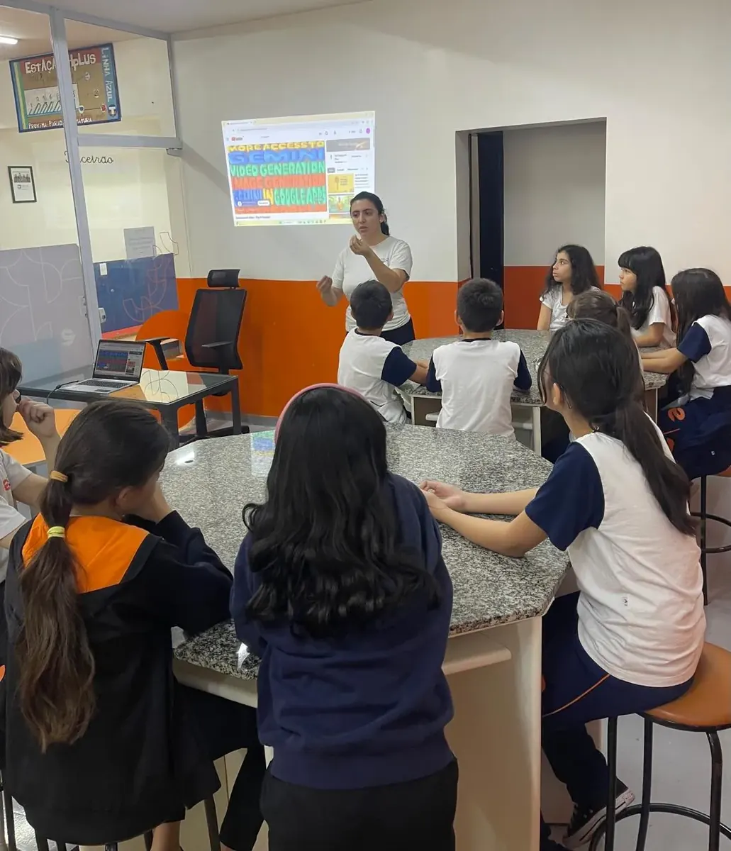 Turma do Fundamental Anos Iniciais em aula sobre inteligência artificial, com a professora e a aula projetada na parede