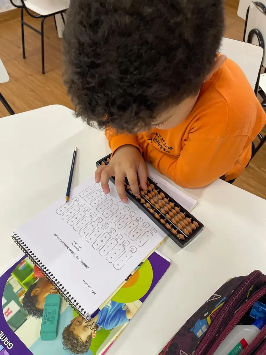 Aluno do COLÉGIO HPLUS fazendo contas no soroban durante a aula de Brain Game