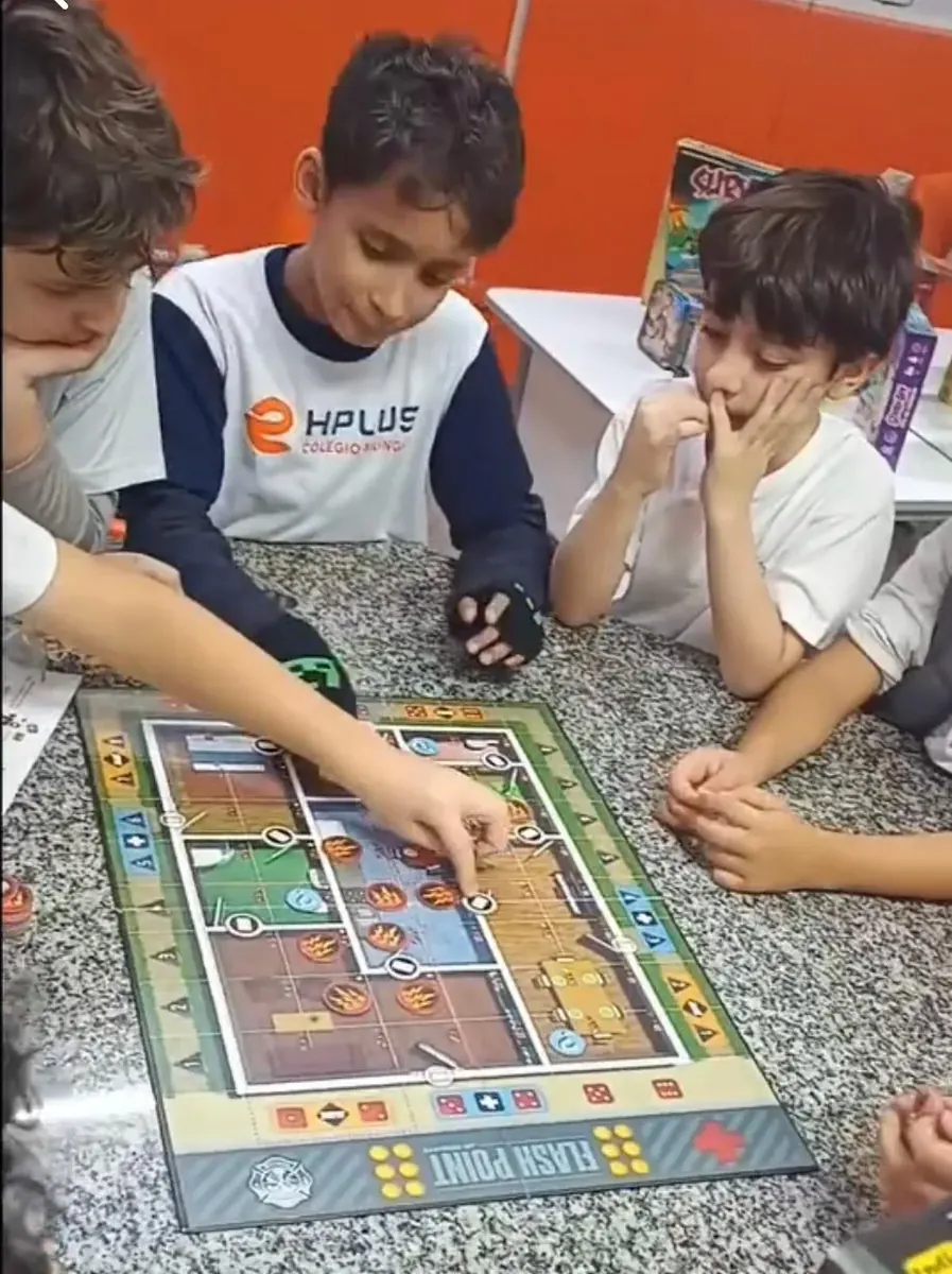 Três alunos concentrados num jogo de tabuleiro cooperativo na aula de Brain Game