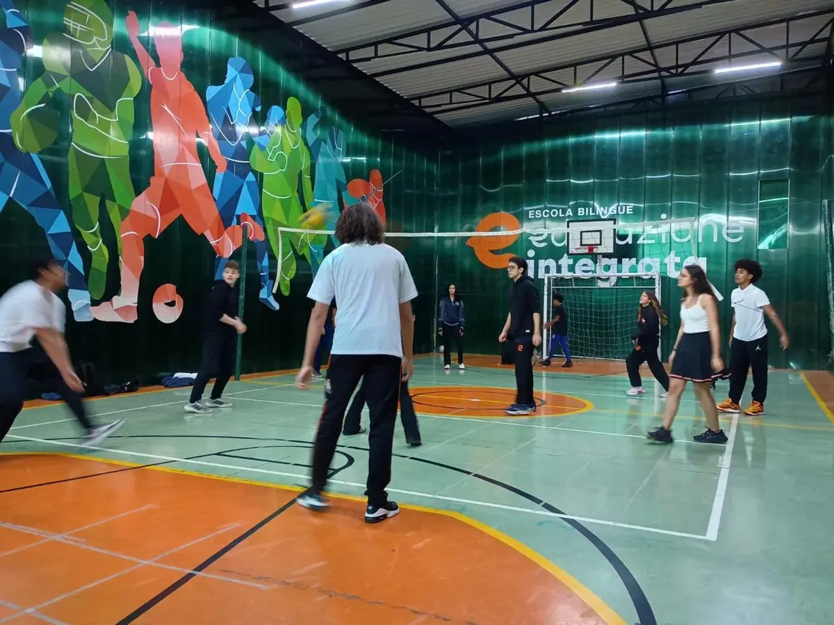 Alunos do Ensino Médio do COLÉGIO HPLUS jogando vôlei na quadra coberta