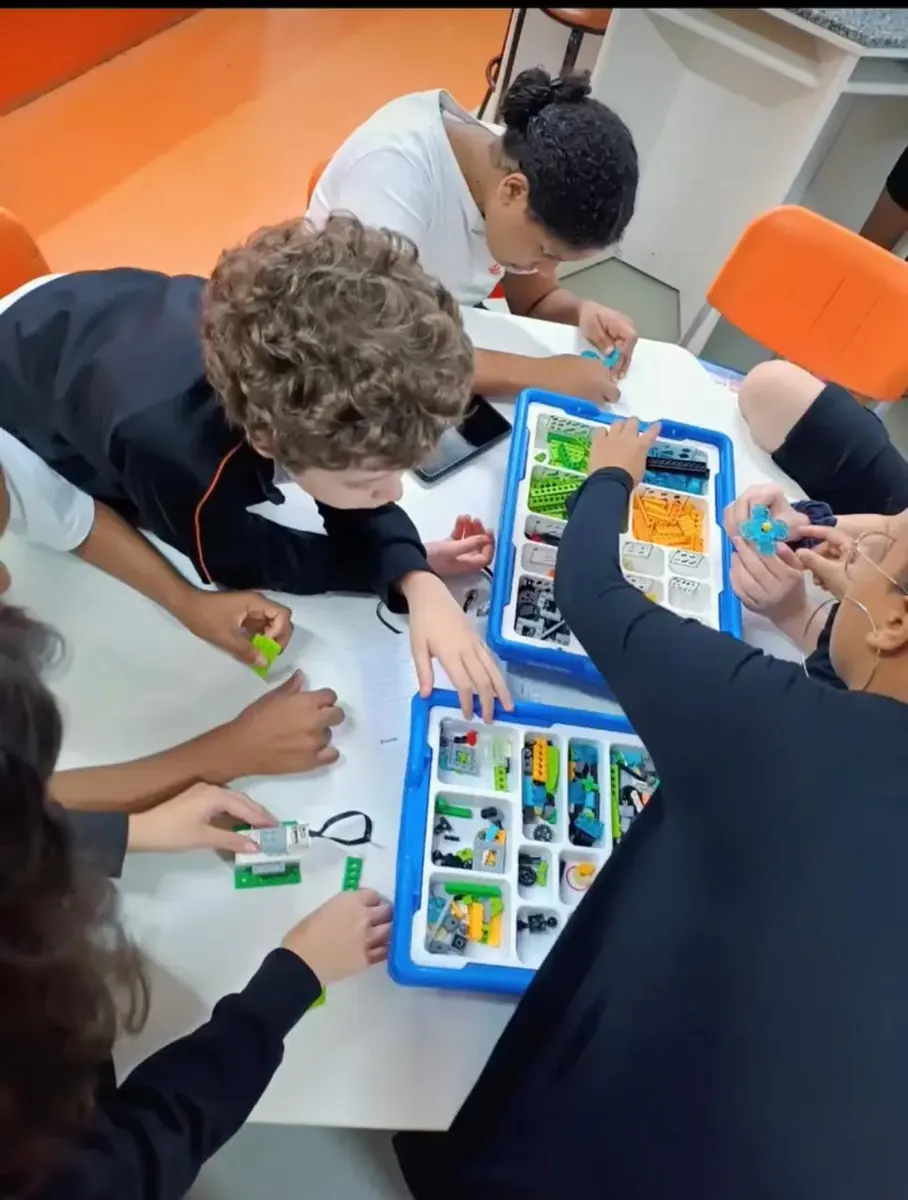 Alunos montando um projeto de robótica com kit de peças e placa programável